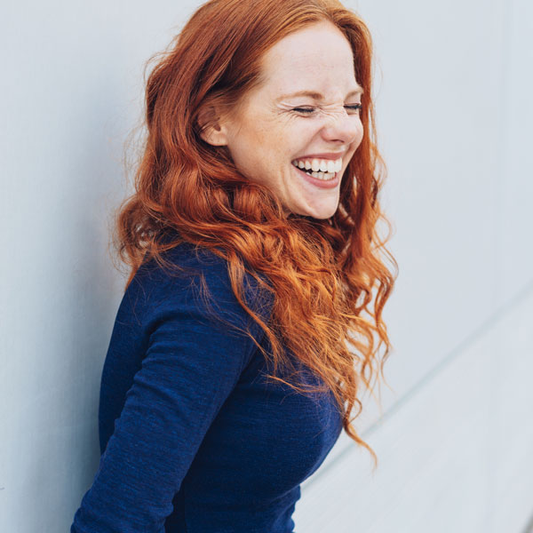 woman with red hair and blue shirt laughing